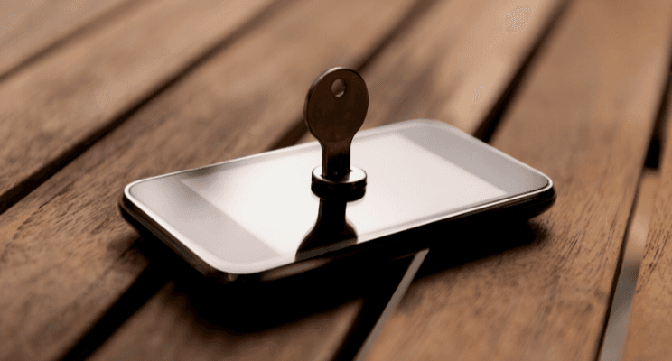 A key inserted into a smartphone screen on a wooden surface – Representing cybersecurity, data protection, and secure financial planning.