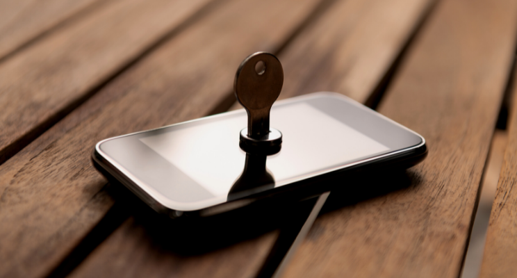 A key inserted into a smartphone screen on a wooden surface – Representing cybersecurity, data protection, and secure financial planning.